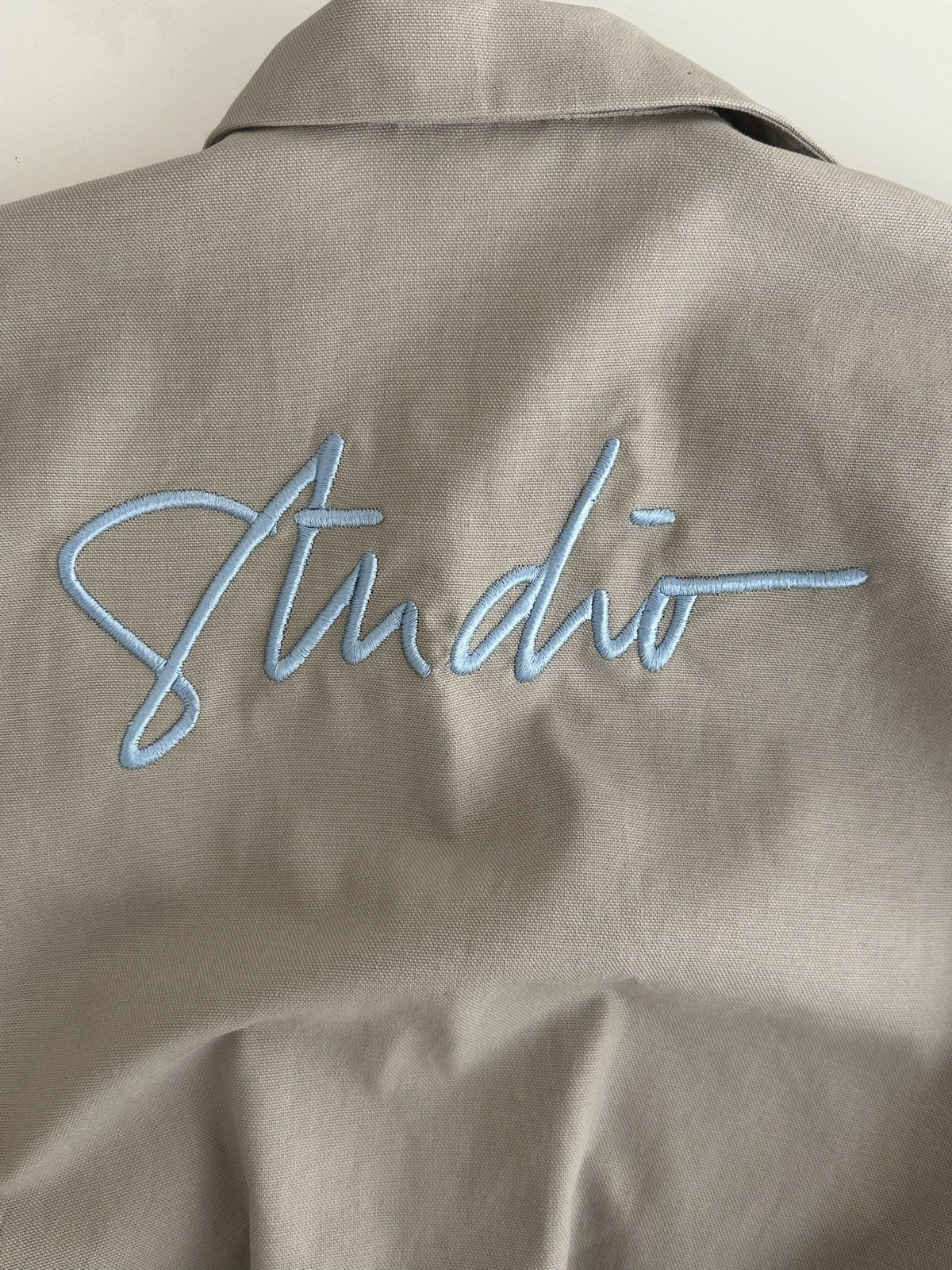 Stickerei „Studio“ in Hellblau auf dem Rücken, Nahaufnahme