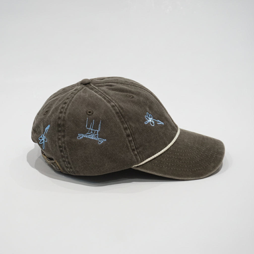 Cap Brown von der Seite mit Skateboard-Stickerei in Hellblau