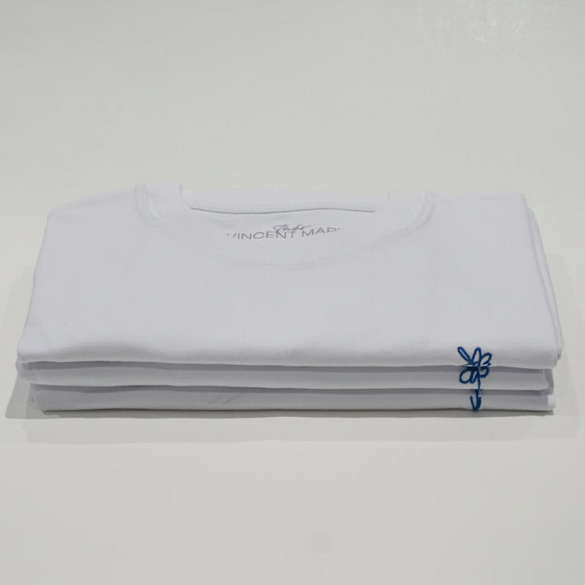 Gestapelte weiße T-Shirts mit blau gestickter Blume