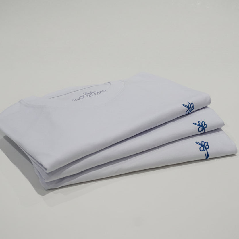 Weiße T-Shirts gestapelt, Blumen-Stickerei von der Seite
