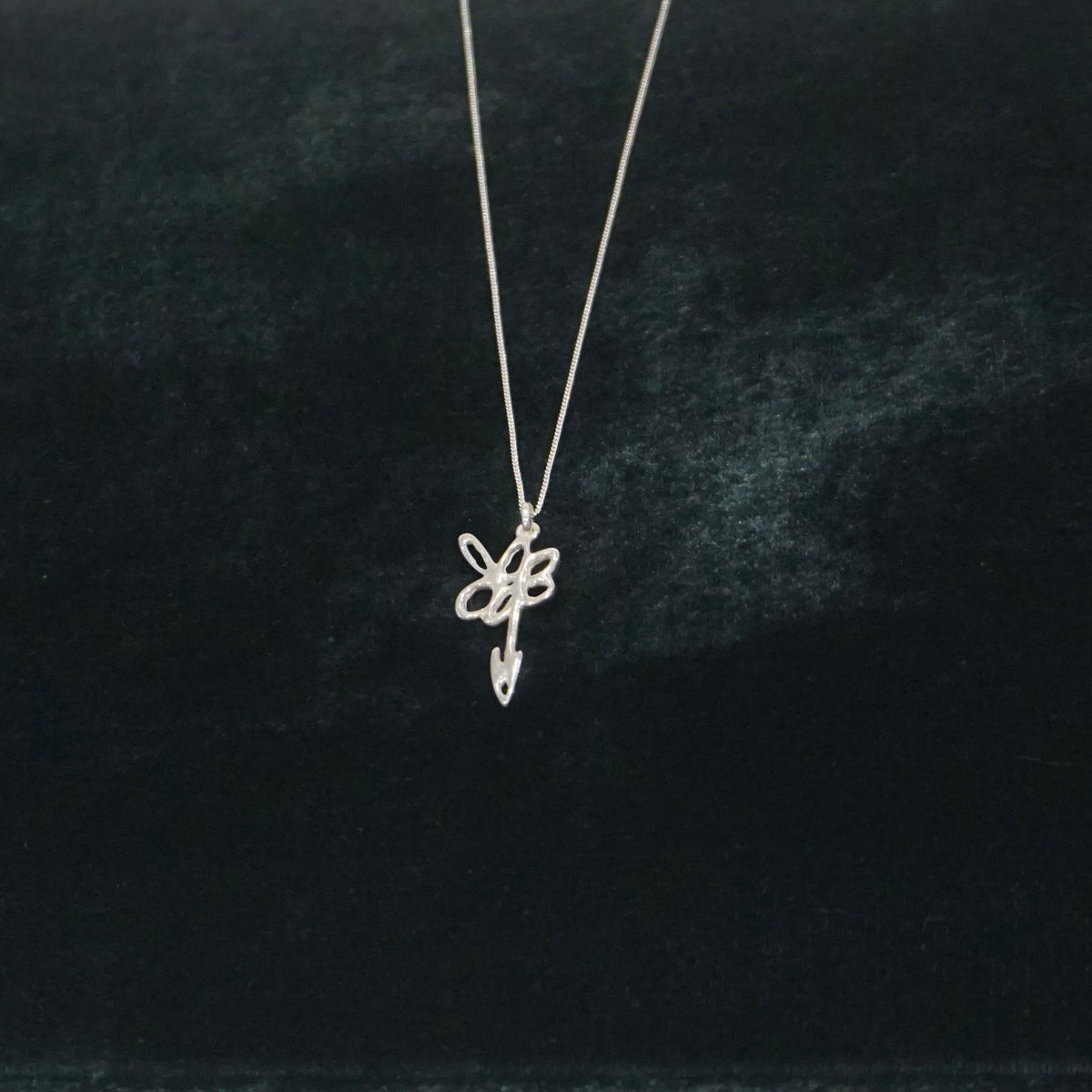 Lei-Kette aus Silber mit Blumenanhänger auf grünem Samt