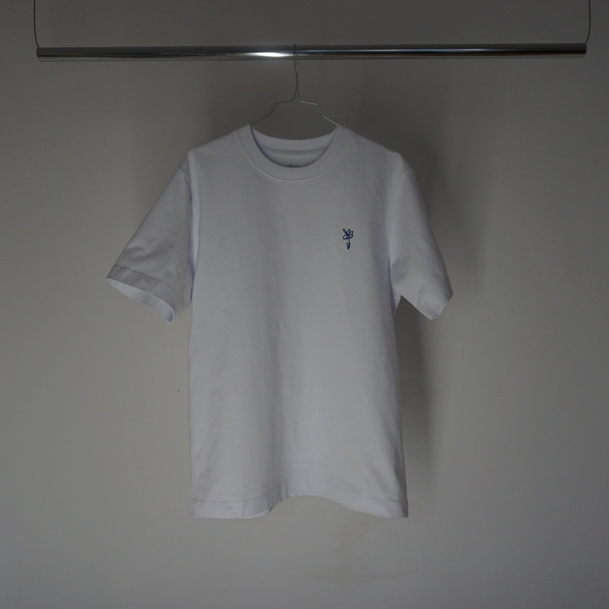 Weißes T-Shirt auf dem Bügel an der Kleiderstange